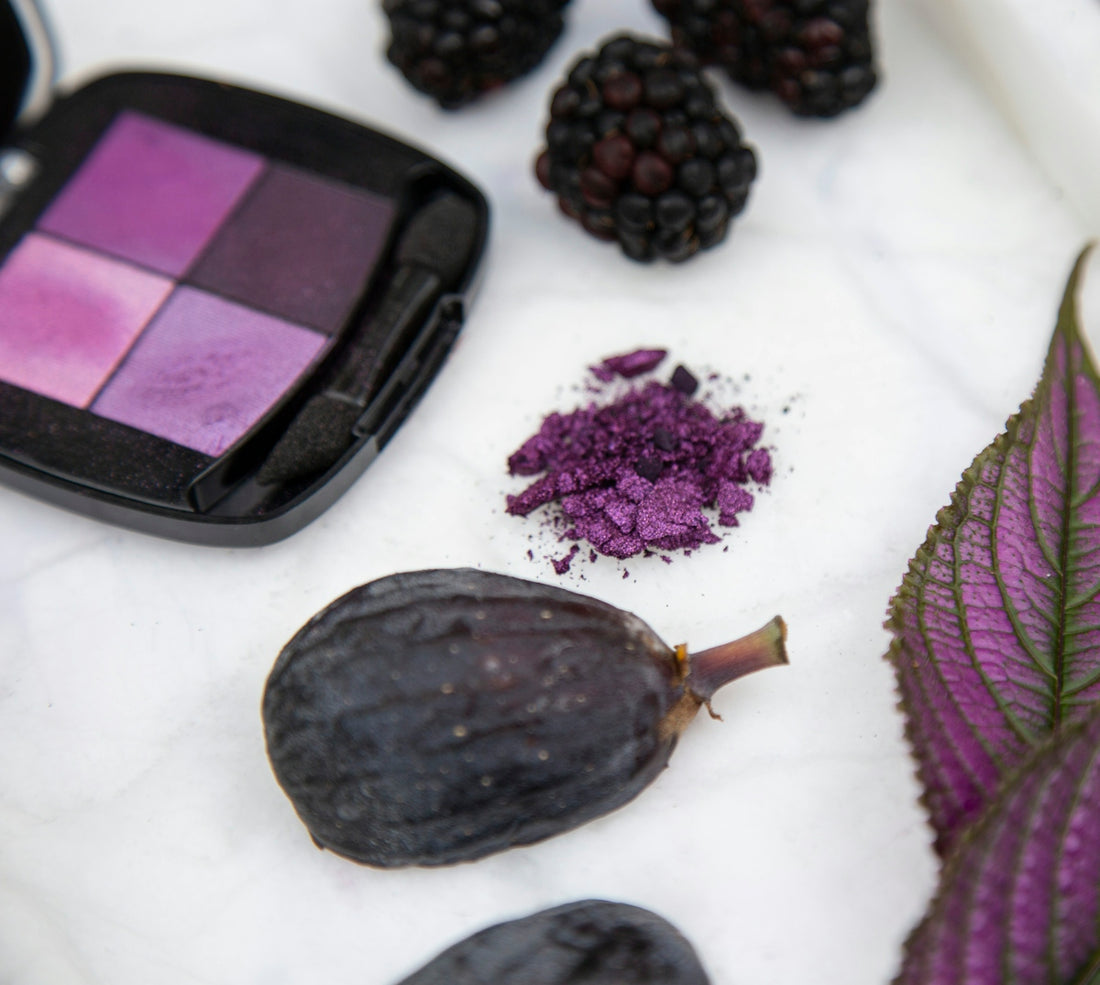 black and purple round fruit beside purple and black eyeshadow palette