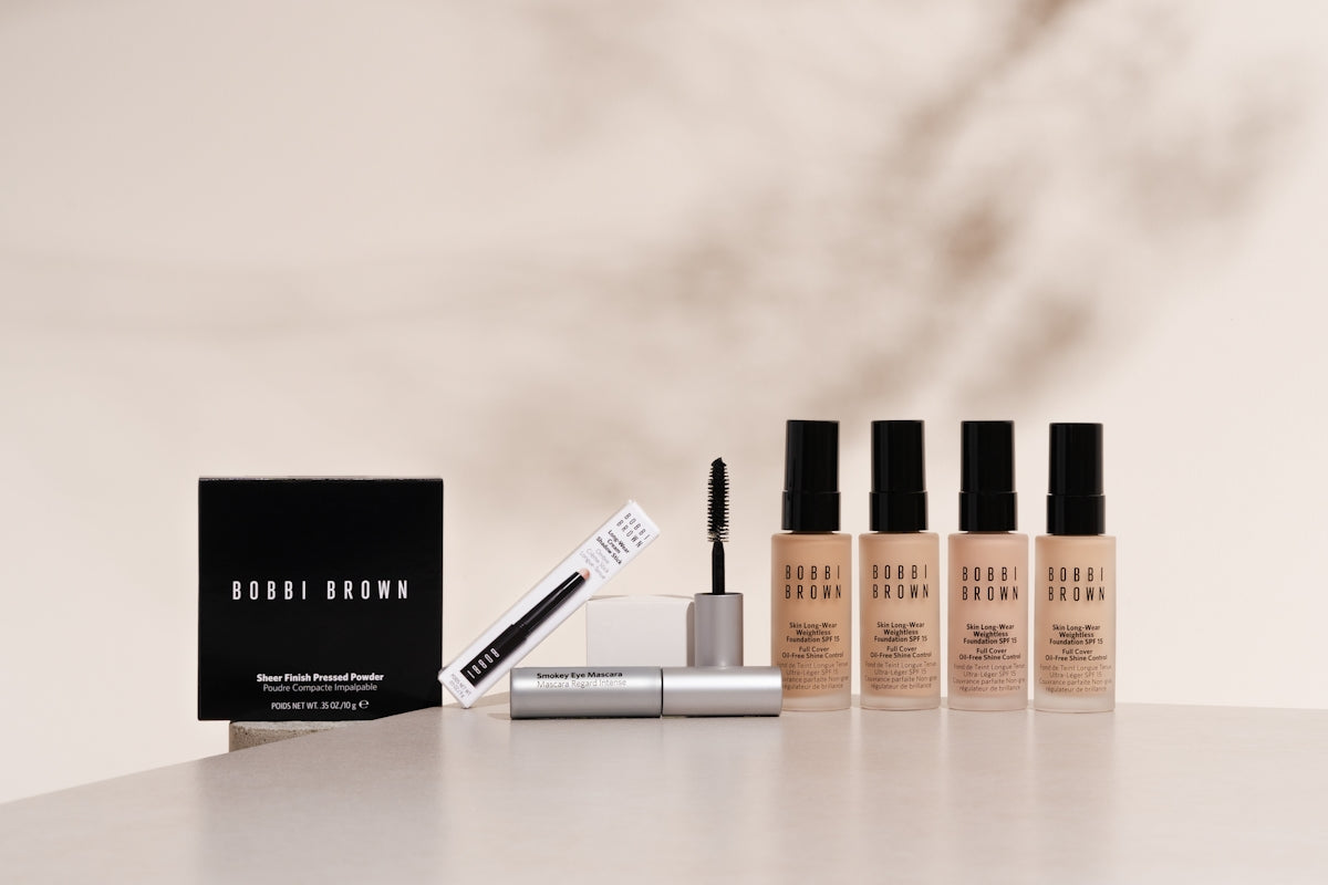 A white table topped with three bottles of makeup