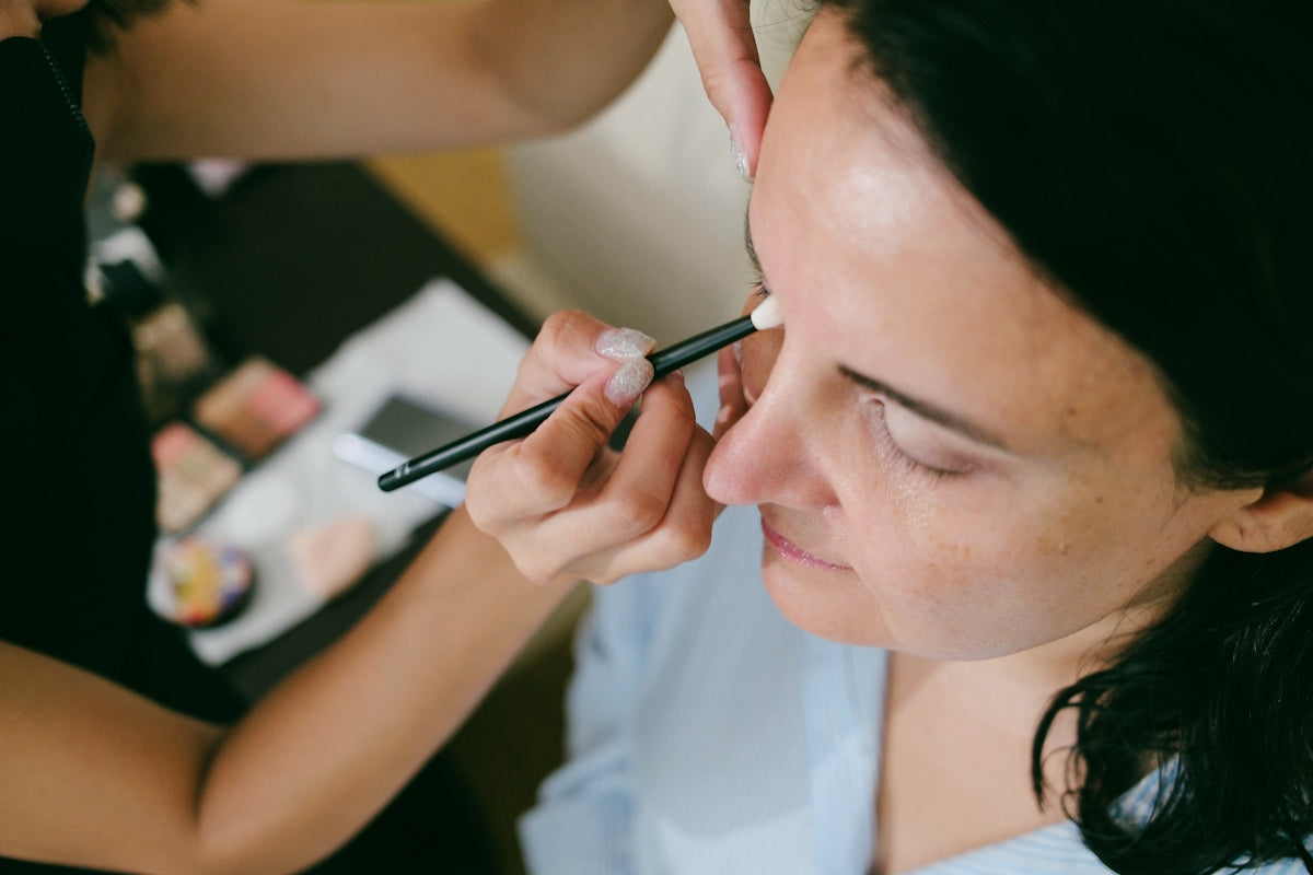 Makeup artist applying eye makeup to a woman.
