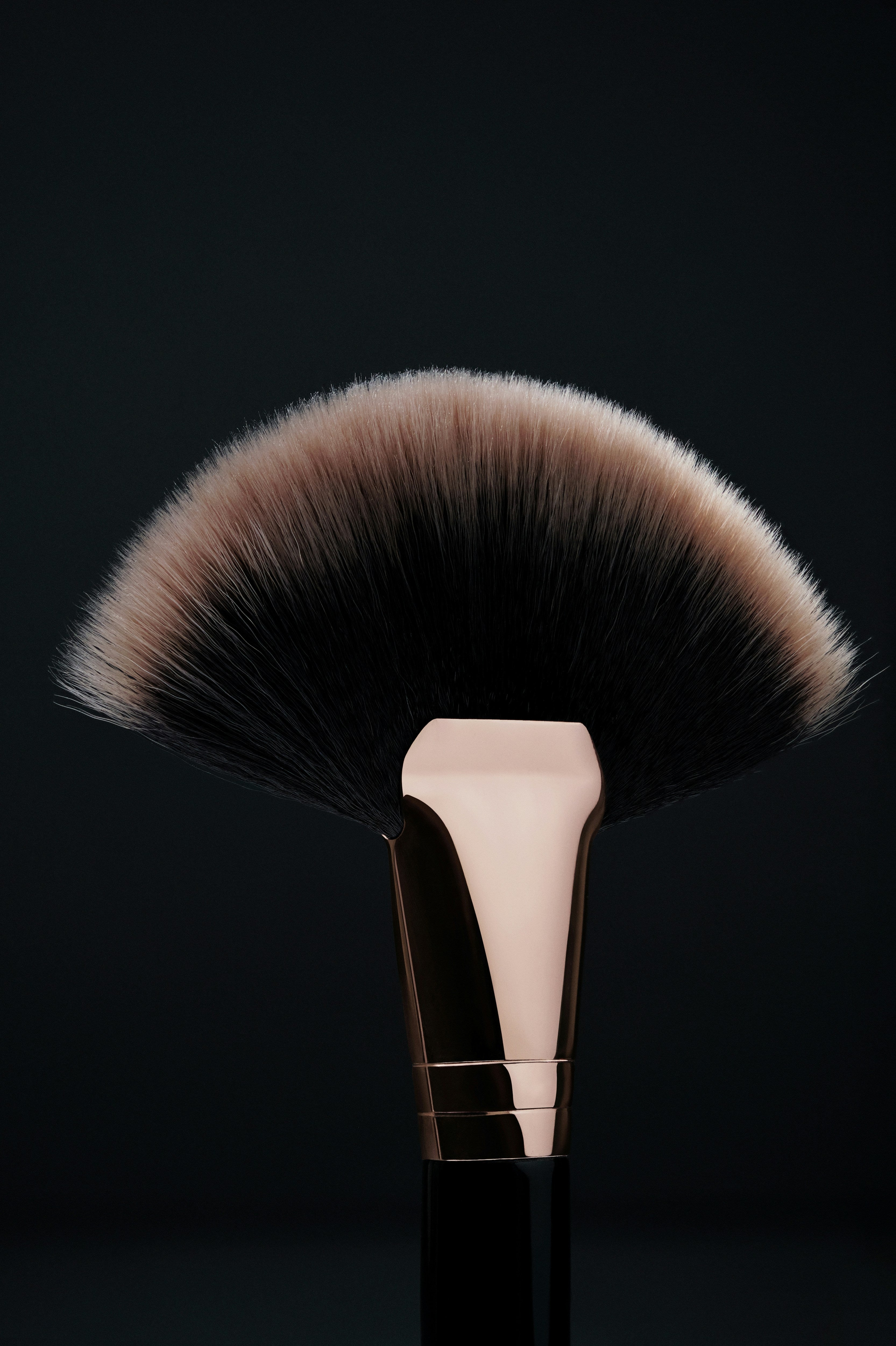 Makeup brush with a fluffy bristle head on a black background